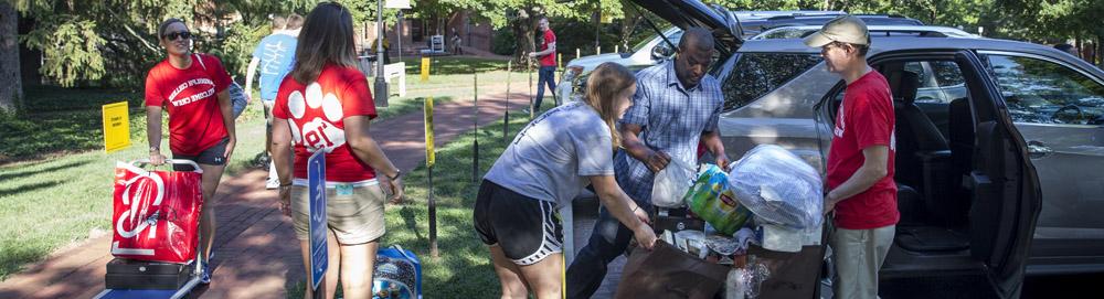 Students help new students and their families unload their cars