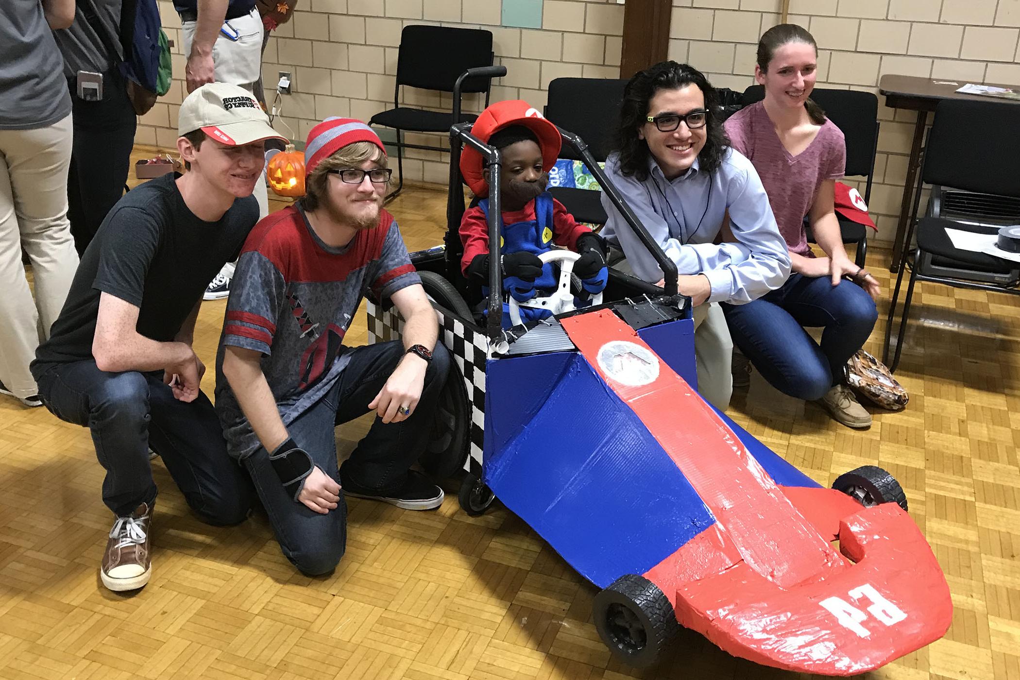 Randolph College physics student present their custom built Mario wheelchair costume to a local boy.