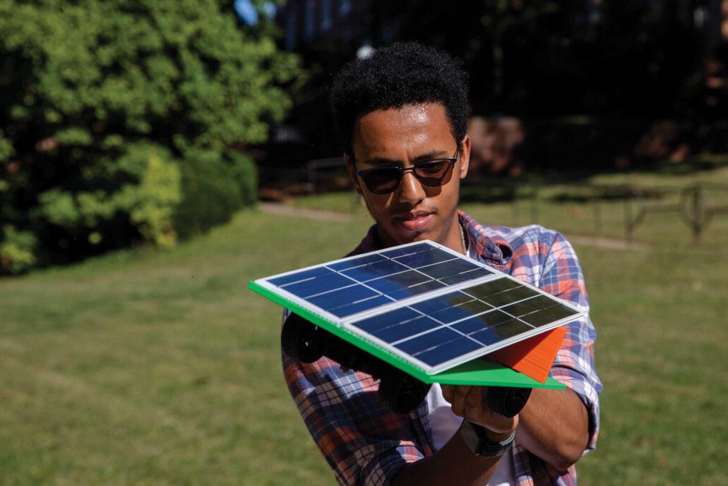 A Randolph College student makes an adjustment to his solar powered car during an outdoor lab session