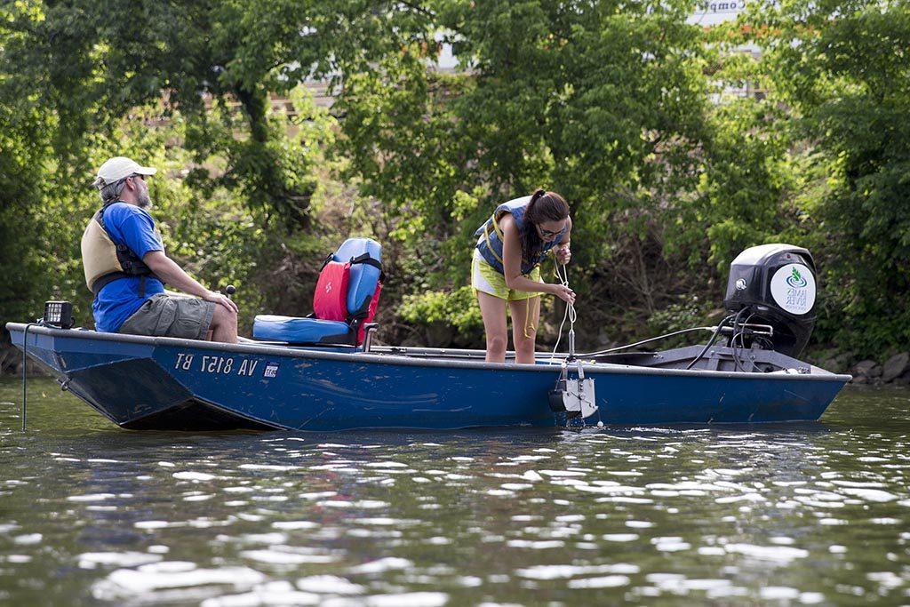 Environmental science students collect water samples near a dam to test for contamination.